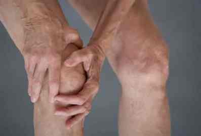 man holding an arthritic knee in pain